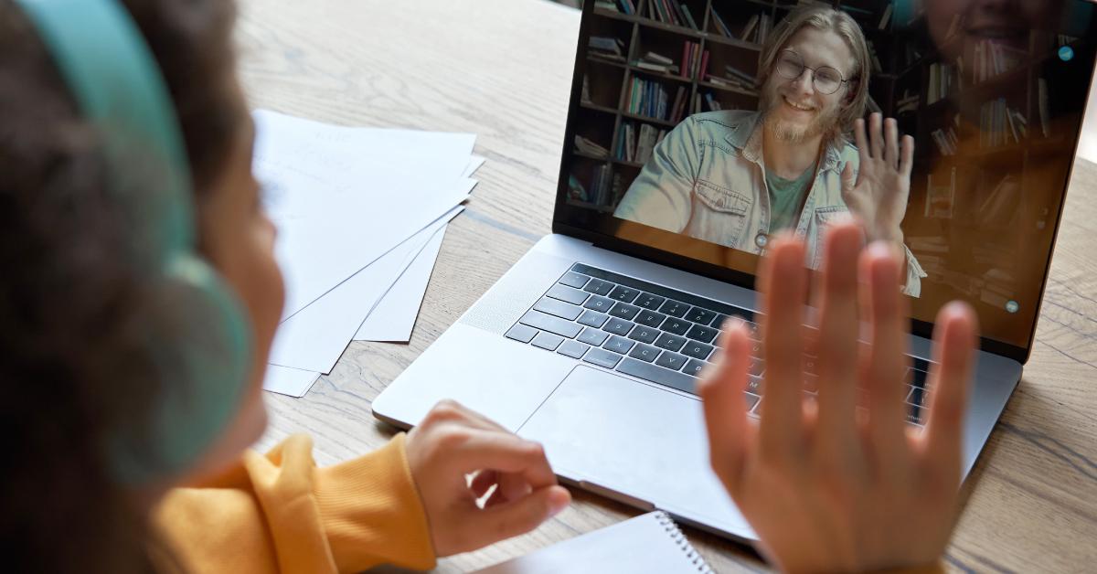 Mujer en una clase de aprendizaje en línea saludando a su profesor al otro lado de la pantalla