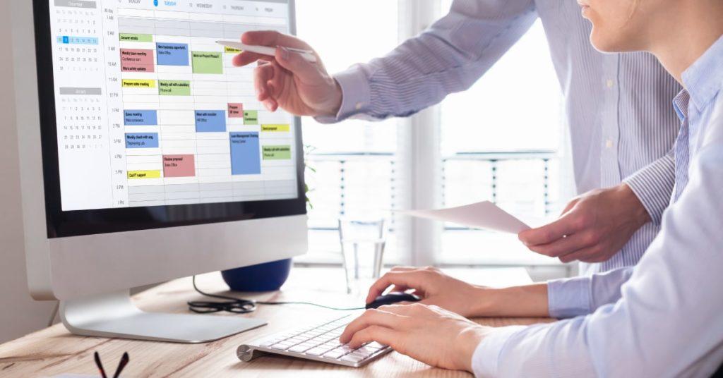 Dos trabajadores utilizando un calendario online para la gestión eficaz del tiempo